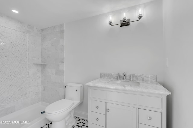 bathroom featuring vanity, toilet, and a tile shower