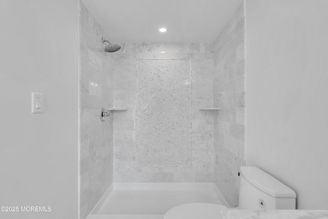 bathroom featuring toilet and a tile shower