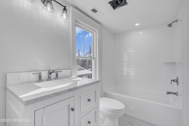 full bathroom with tiled shower / bath, vanity, and toilet