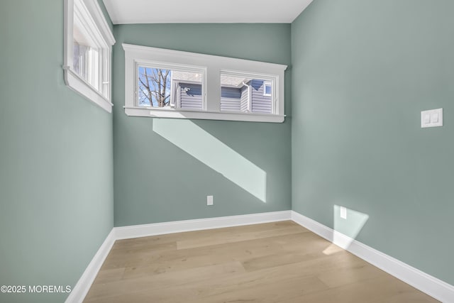 spare room featuring lofted ceiling and light hardwood / wood-style flooring