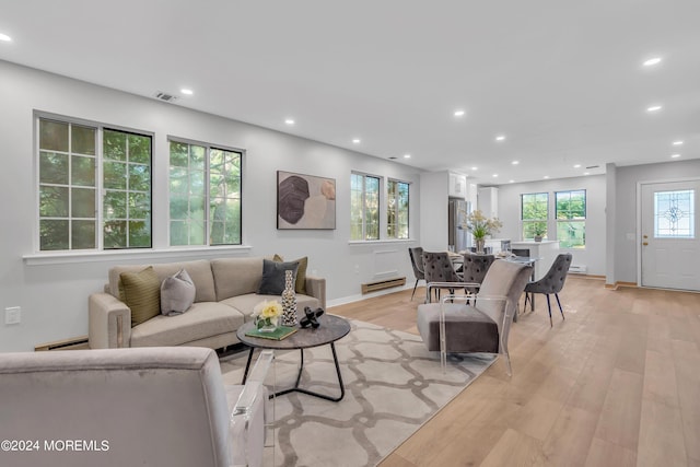 living room with a baseboard heating unit and light hardwood / wood-style flooring