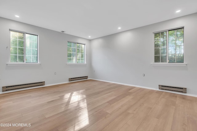 unfurnished room featuring light wood-type flooring and baseboard heating