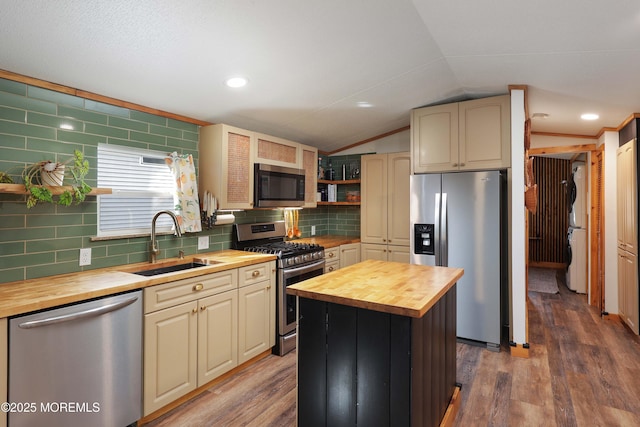 kitchen featuring lofted ceiling, butcher block countertops, sink, stainless steel appliances, and a kitchen island