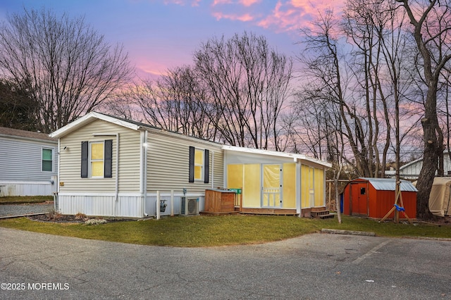 manufactured / mobile home featuring a lawn and a storage unit