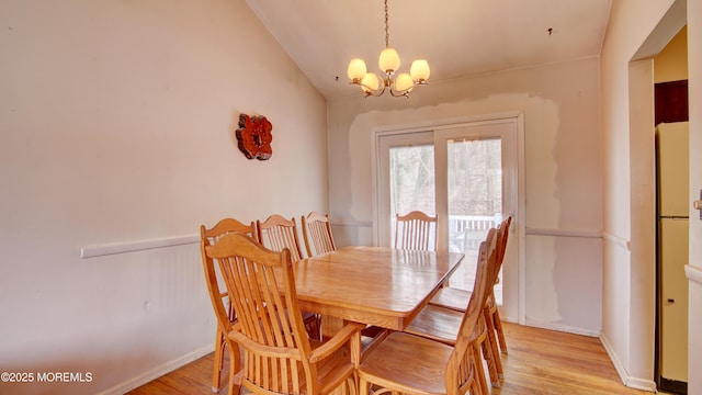 dining room featuring a chandelier, light wood-type flooring, lofted ceiling, and baseboards