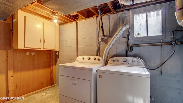 clothes washing area featuring washing machine and dryer and cabinet space