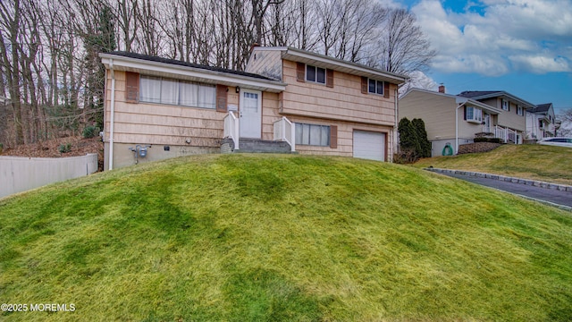 tri-level home featuring a garage, driveway, and a front lawn