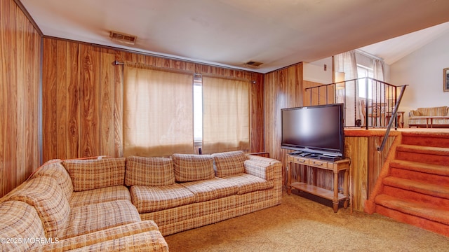 living room with wood walls, carpet, stairs, and visible vents