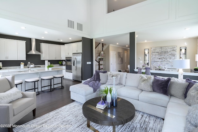 living room featuring hardwood / wood-style flooring, a towering ceiling, and sink