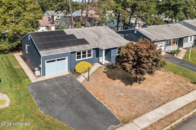 view of front of property with a garage, a front lawn, and solar panels