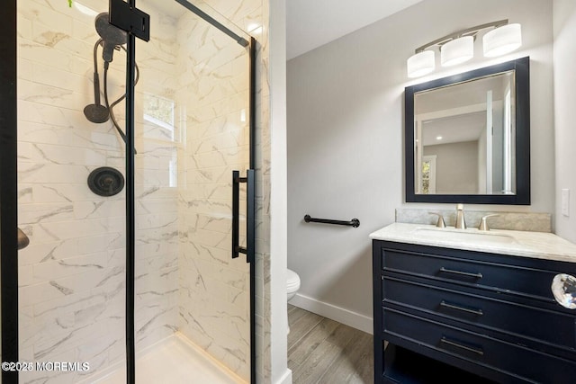 bathroom with a tile shower, vanity, hardwood / wood-style flooring, and toilet