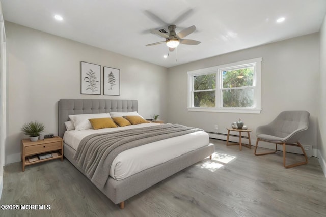 bedroom featuring ceiling fan, dark hardwood / wood-style floors, and a baseboard heating unit