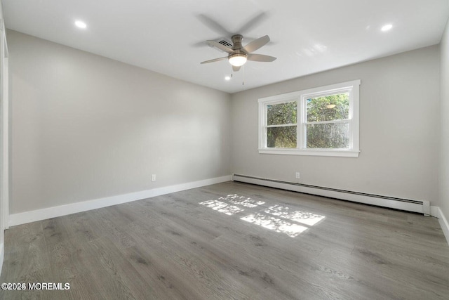 unfurnished room featuring a baseboard heating unit, ceiling fan, and light wood-type flooring