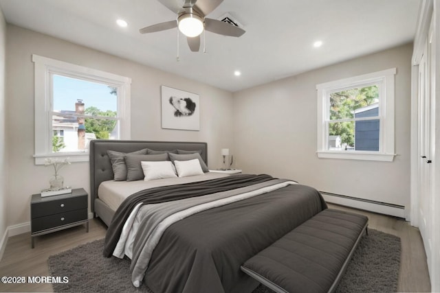 bedroom with hardwood / wood-style floors, ceiling fan, and baseboard heating