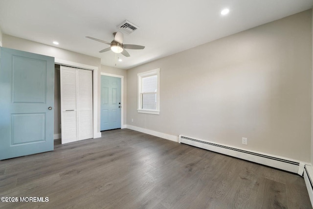 unfurnished bedroom with a closet, dark hardwood / wood-style floors, ceiling fan, and baseboard heating