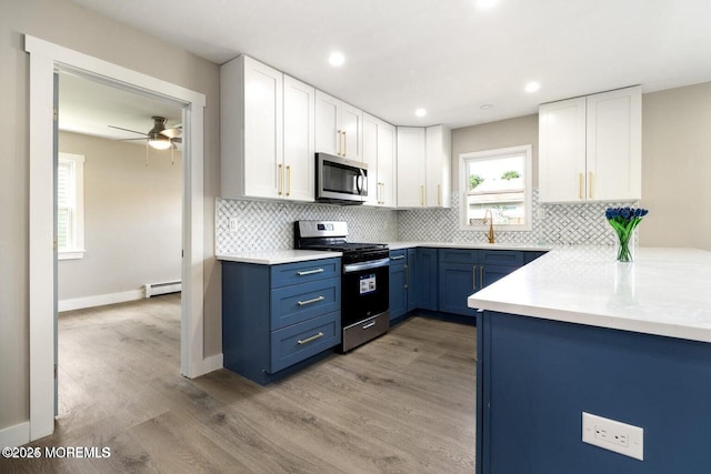 kitchen with appliances with stainless steel finishes, white cabinetry, a baseboard radiator, light hardwood / wood-style floors, and blue cabinetry