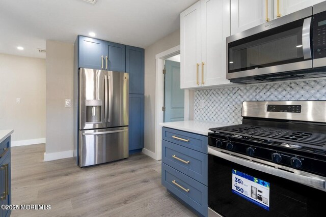 kitchen featuring blue cabinetry, white cabinetry, light hardwood / wood-style flooring, appliances with stainless steel finishes, and decorative backsplash