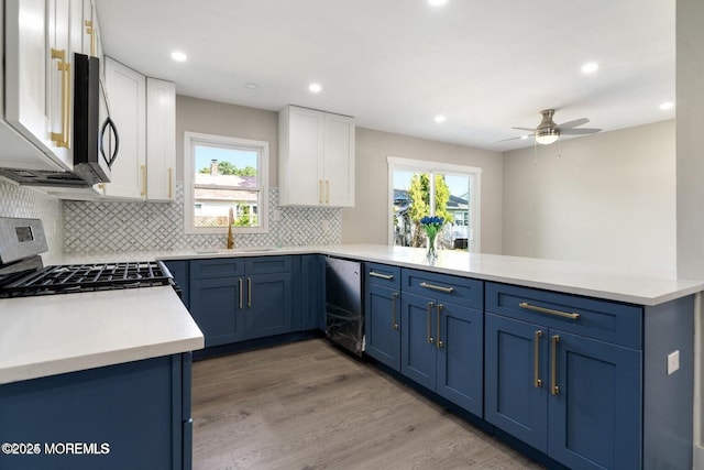 kitchen featuring appliances with stainless steel finishes, blue cabinets, sink, white cabinets, and kitchen peninsula