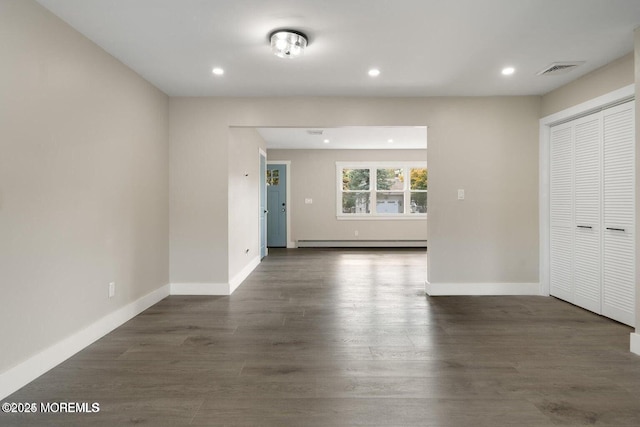 unfurnished room with dark wood-type flooring and a baseboard radiator