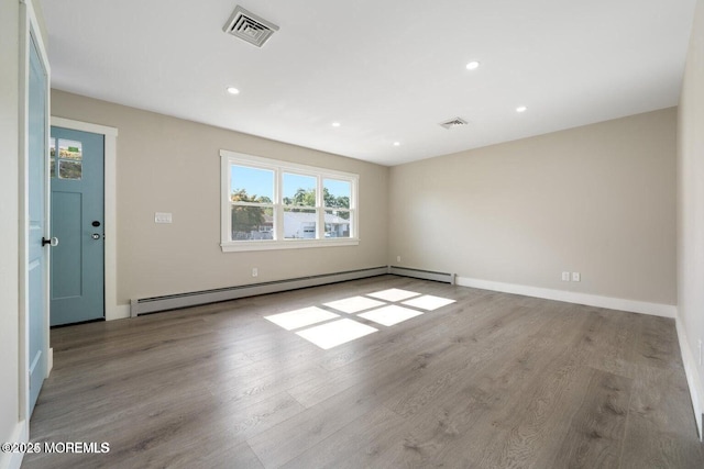 unfurnished room featuring light wood-type flooring and baseboard heating