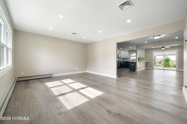 unfurnished living room with baseboard heating and light hardwood / wood-style floors