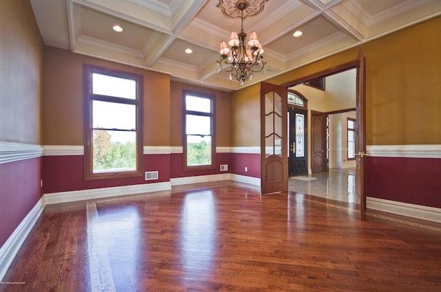 spare room featuring a chandelier, hardwood / wood-style flooring, ornamental molding, coffered ceiling, and beam ceiling