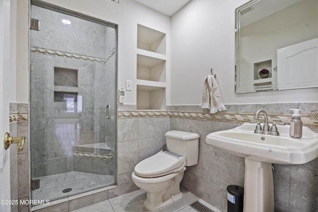 bathroom with a stall shower, visible vents, toilet, a wainscoted wall, and tile walls