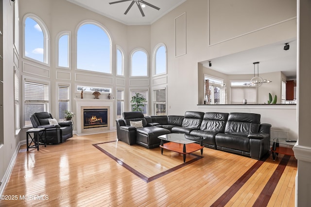 living area featuring ornamental molding, hardwood / wood-style floors, a glass covered fireplace, and a high ceiling