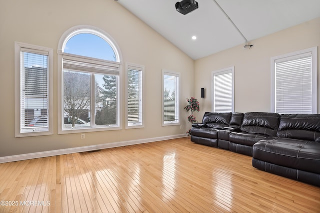 unfurnished living room featuring high vaulted ceiling, wood-type flooring, and baseboards