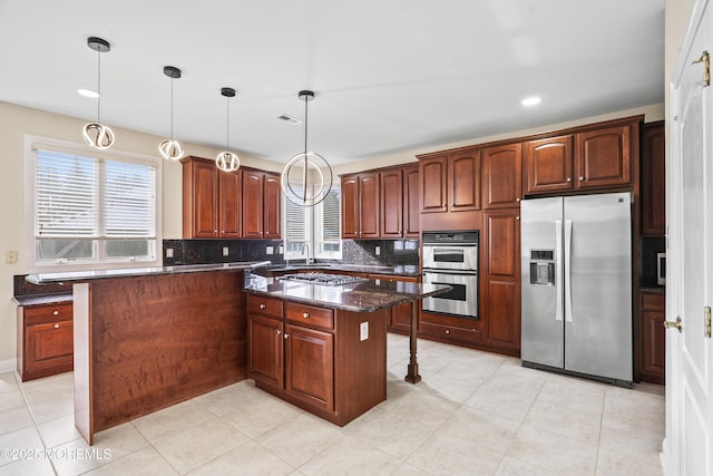 kitchen featuring a kitchen island, visible vents, hanging light fixtures, appliances with stainless steel finishes, and backsplash