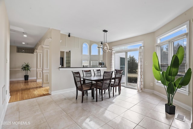 dining space with light tile patterned floors, baseboards, visible vents, and a notable chandelier