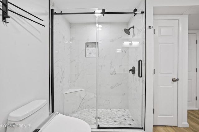 full bath featuring a marble finish shower, wood finished floors, and toilet