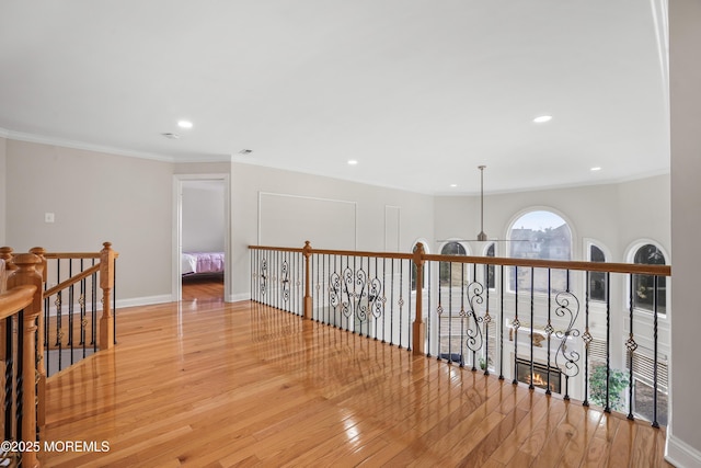 hallway featuring hardwood / wood-style flooring, recessed lighting, an upstairs landing, baseboards, and crown molding