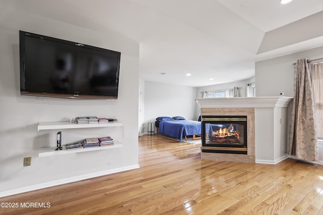 living room featuring recessed lighting, baseboards, a multi sided fireplace, and wood finished floors