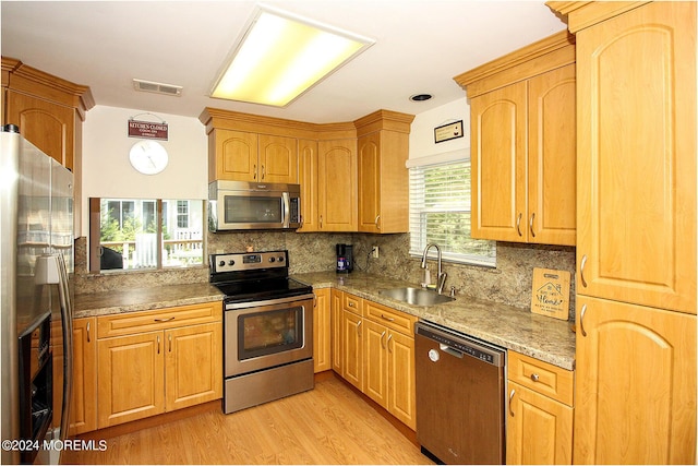 kitchen featuring stainless steel appliances, a sink, visible vents, light wood-style floors, and backsplash