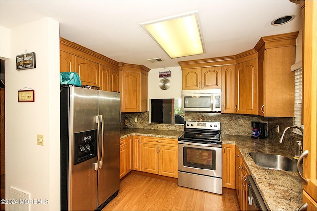 kitchen featuring visible vents, dark stone counters, appliances with stainless steel finishes, light wood-type flooring, and a sink