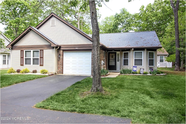 view of front of home with a garage, driveway, brick siding, and a front yard