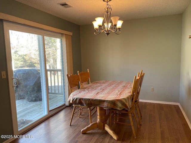 dining area featuring visible vents, a notable chandelier, baseboards, and wood finished floors