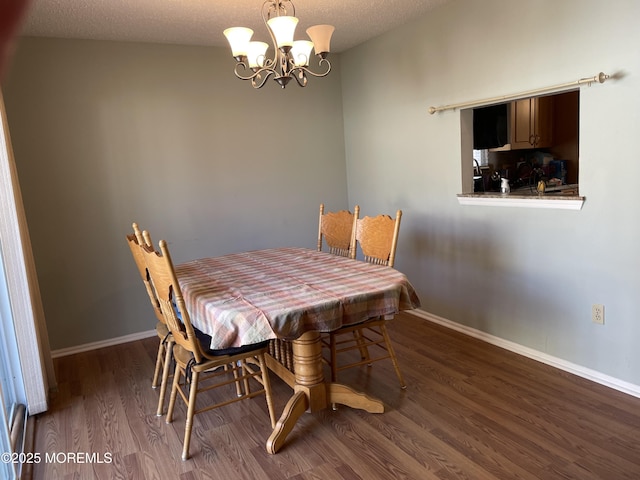 dining room featuring a textured ceiling, baseboards, a chandelier, and wood finished floors