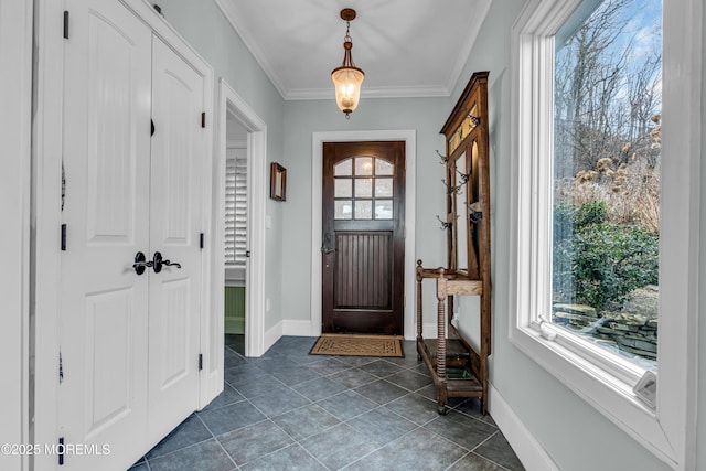 foyer entrance with dark tile patterned floors, baseboards, and ornamental molding