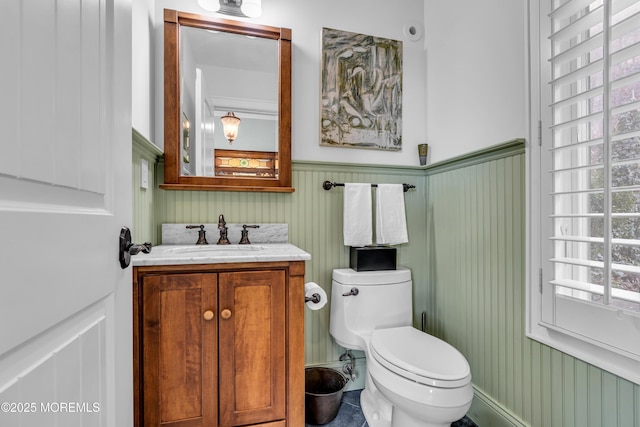 bathroom with a wainscoted wall, vanity, and toilet