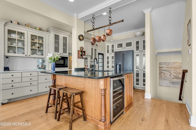 kitchen with crown molding, beverage cooler, a sink, and a kitchen breakfast bar