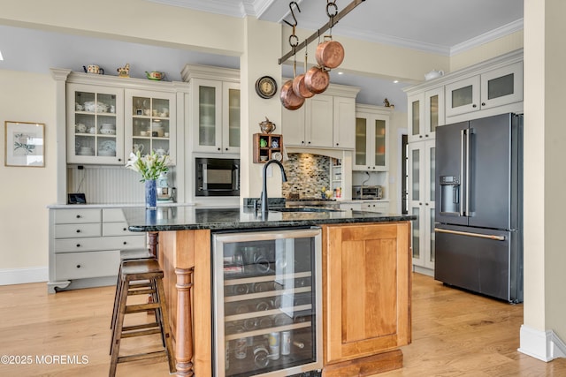 kitchen featuring beverage cooler, light wood-style floors, crown molding, black appliances, and a sink