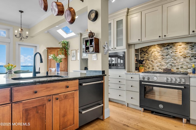 kitchen featuring decorative backsplash, dark stone countertops, stainless steel stove, light wood-type flooring, and a sink