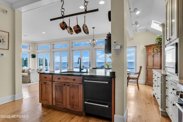 kitchen with ornamental molding, vaulted ceiling, light wood-type flooring, black microwave, and a sink