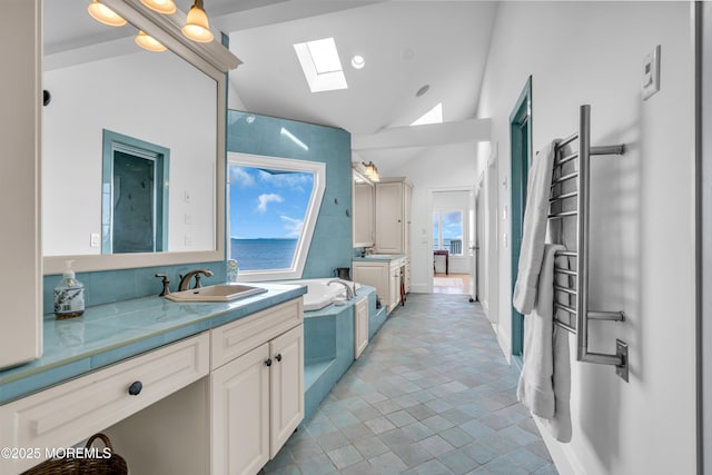 interior space featuring high vaulted ceiling, a skylight, a garden tub, and vanity