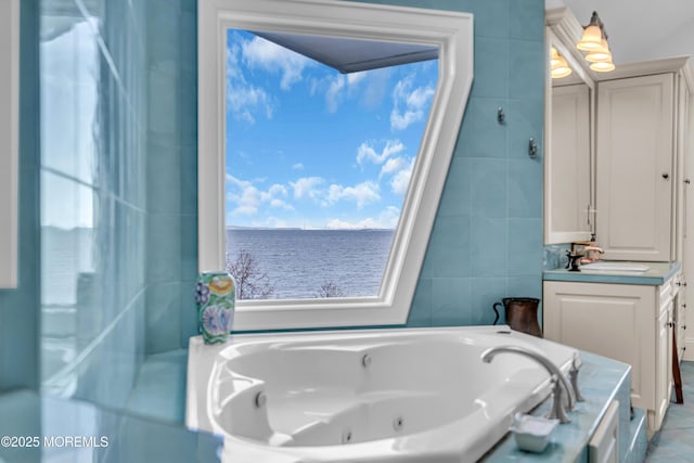 full bathroom featuring tile walls, a water view, vanity, a tub with jets, and tile patterned floors