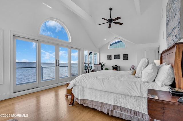 bedroom with access to exterior, a ceiling fan, high vaulted ceiling, light wood-type flooring, and beamed ceiling