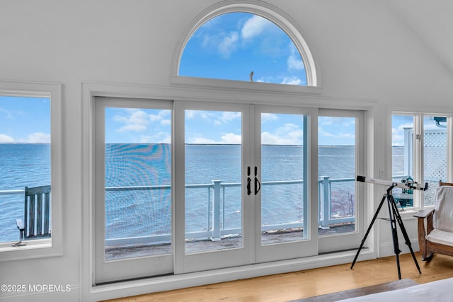 entryway featuring french doors, a water view, vaulted ceiling, and wood finished floors