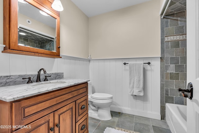 full bath featuring tile patterned flooring, wainscoting, vanity, and toilet